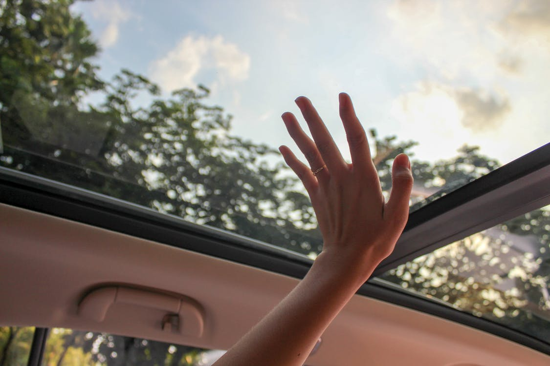 A hand touching a glass sunroof