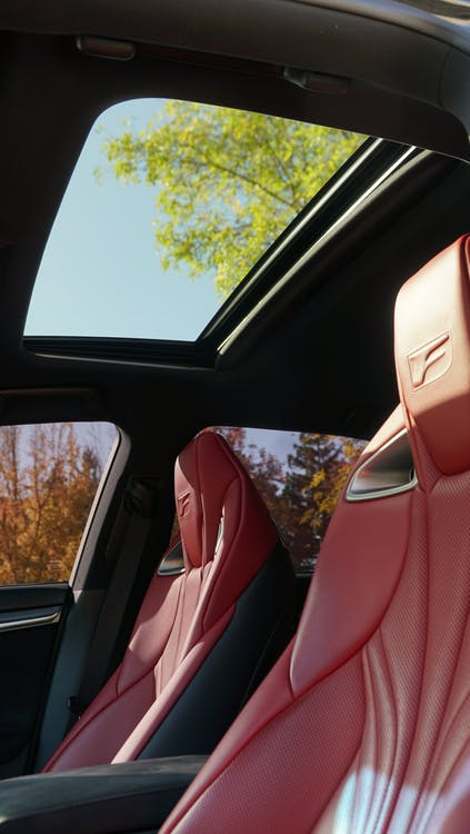 A car interior with red seat covers and a sunroof.